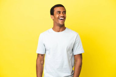 Sarı arka planda oturan Afrikalı yakışıklı adam gülüyor.