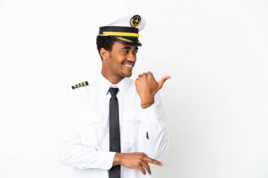 İzole edilmiş beyaz arka plan üzerinde Afrikalı Amerikan Uçak Pilotu bir ürünü sunmak için kenarı işaret ediyor