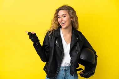 Sarı arka planda izole edilmiş motosiklet kasklı genç sarışın bir kadın.