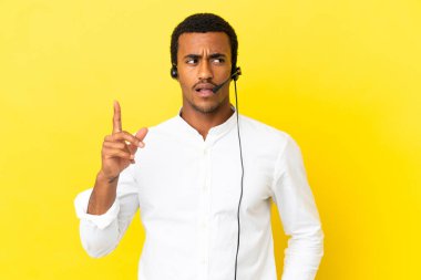 Afro-Amerikalı bir pazarlamacı, izole edilmiş sarı arka plan üzerinde çalışan bir kulaklıkla çalışıyor.