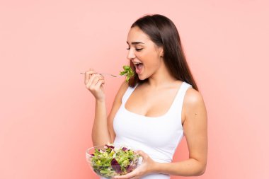 Pembe arka planda salata tutan beyaz bir kadın.