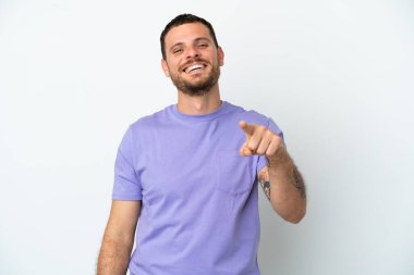 Beyaz arka planda izole edilmiş genç Brezilyalı adam şaşırmış ve ön tarafı işaret ediyor.