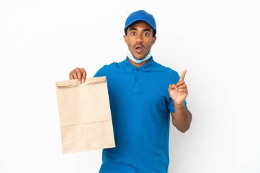Afro-Amerikalı bir adam beyaz arka planda izole edilmiş bir paket yiyecek alıyor. Çözümü bulmak için parmağını kaldırıyor.