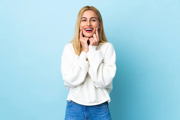 Jovem Mulher Loira Uruguaia Sobre Fundo Azul Isolado Sorrindo Com — Fotografia de Stock