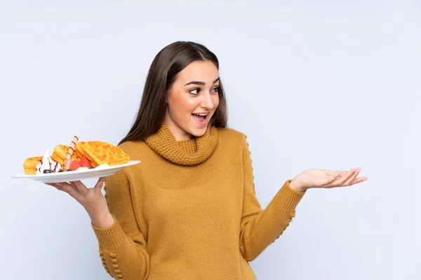 Jonge Kaukasische Vrouw Houden Wafels Geïsoleerd Blauwe Achtergrond Met Verrassing — Stockfoto