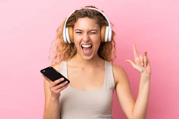 Νεαρή Ξανθιά Γυναίκα Απομονωμένη Ροζ Φόντο Ακούγοντας Μουσική Μια Κινητή — Φωτογραφία Αρχείου