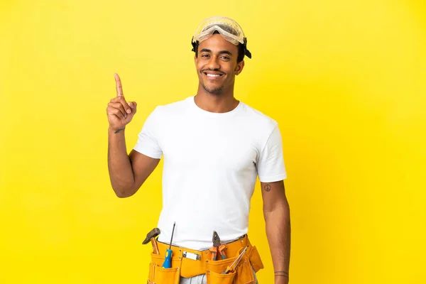 African American electrician man over isolated yellow wall pointing up a great idea