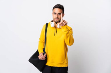 Spor çantalı genç adam beyaz arka planda izole edilmiş ciddi ifadeli birini sayıyor.