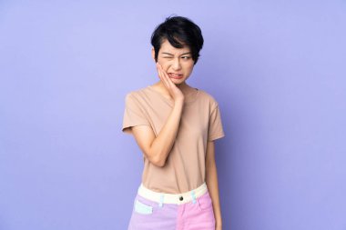 Genç Vietnamlı kadın, kısa saçlı, izole edilmiş mor arkaplan ve diş ağrısı var.