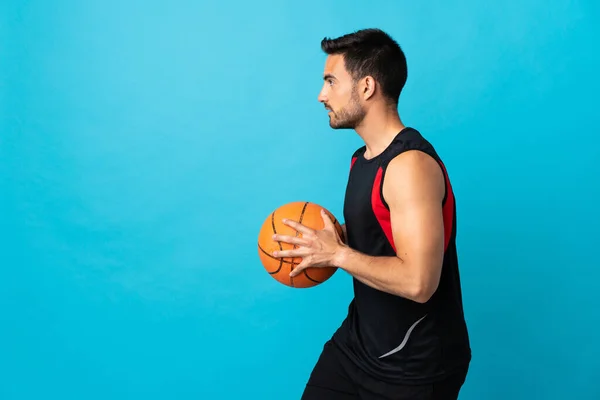 Jonge Knappe Man Geïsoleerd Blauwe Achtergrond Basketbal Spelen — Stockfoto