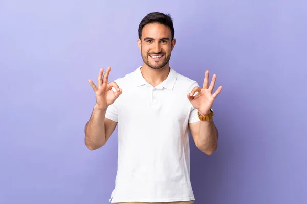 Joven Hombre Guapo Aislado Sobre Fondo Púrpura Mostrando Signo Con —  Fotos de Stock