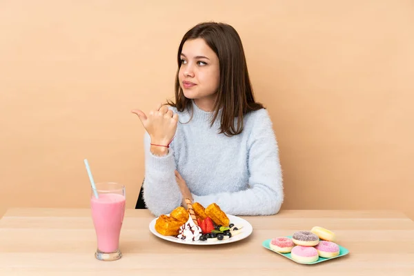 Chica Adolescente Comiendo Gofres Aislados Sobre Fondo Beige Apuntando Hacia — Foto de Stock