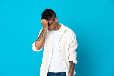 Mavi arka planda baş ağrısı olan genç Brezilyalı bir adam izole edilmiş.