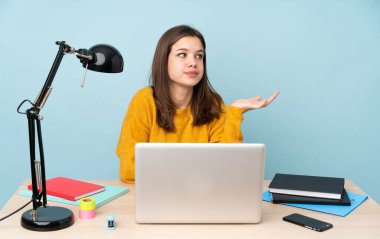 Öğrenci kız evinde çalışıyor. Mavi arka planda izole edilmiş. Bir şeyi anlamadığı için mutsuz.