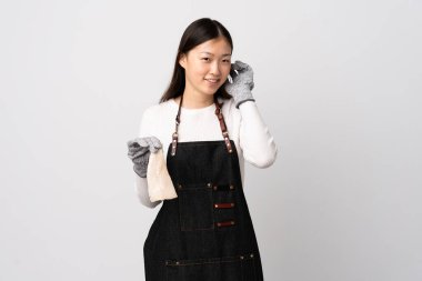 Çinli balıkçı önlük takıyor ve soyutlanmış beyaz arka planda çiğ balık tutuyor.