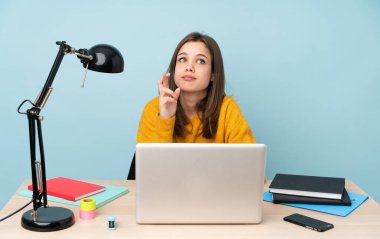 Öğrenci kız, mavi arka planda izole bir şekilde evinde ders çalışıyor.