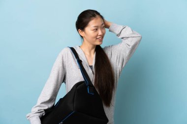 Spor çantalı genç Çinli kadın izole edilmiş mavi arka planda bir fikir düşünüyor.