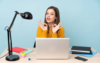 Öğrenci kız evinde çalışıyor. Mavi arka planda izole edilmiş. Parmaklarıyla 