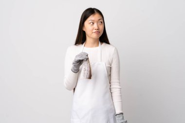 Çinli balıkçı önlük takıyor ve soyutlanmış beyaz arka planda çiğ balık tutuyor.