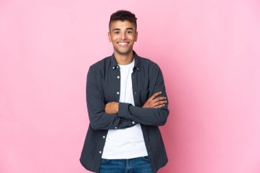 Pembe arka planda izole edilmiş genç Brezilyalı adam kollarını ön cephede çapraz tutuyor.