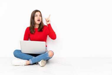 Beyaz arkaplanda bilgisayar ile çalışan tenaager kız bir parmak kaldırarak çözümü gerçekleştirmek niyetinde