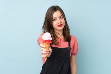 Kornet dondurması tutan genç kız mavi arka planda izole edilmiş.