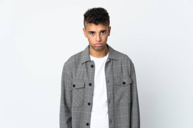 Genç Brezilyalı adam üzgün bir ifadeyle beyaz arka planda izole edilmiş.