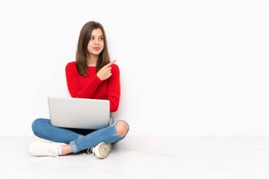 Beyaz arkaplanda bilgisayar ile çalışan tenaager kız bir ürün sunmak için kenarı işaret ediyor