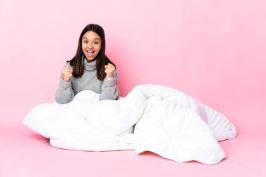 Genç melez kadın pijamasını giymiş yerde oturmuş zaferi kutluyor.