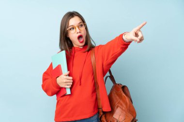 Elinde mavi arka planda izole edilmiş kitaplar tutan öğrenci kız.