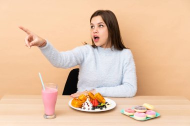 Bej arka planda izole edilmiş waffle yiyen genç kız...