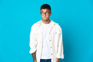 Genç Brezilyalı bir adam mavi arka planda izole edilmiş.