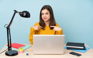 Öğrenci kız evinde çalışıyor. Mavi arka planda, şaşırmış bir yüz ifadesi var.