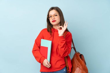 Mavi arka planda izole edilmiş kitapları tutan öğrenci kız parmaklarıyla 