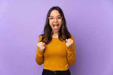 Mor arka planda izole edilmiş genç melez kadın galibiyeti kutluyor.