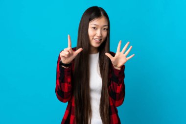 Soyutlanmış mavi arka plan üzerinde genç Çinli kız parmaklarıyla yediyi sayıyor