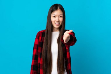 Soyutlanmış mavi arka planda genç Çinli kız iyi bir anlaşma için el sıkışıyor.