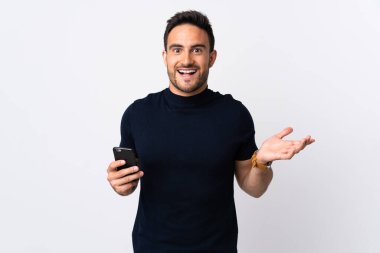 Beyaz arka planda izole edilmiş ve şok olmuş bir yüz ifadesi olan cep telefonu kullanan beyaz bir adam.