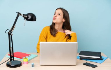 Evinde okuyan öğrenci kız yorgun ve hasta bir ifadeyle mavi arka planda izole edilmiş.