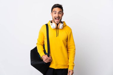 Spor çantalı genç bir adam beyaz arka planda, şaşırmış bir yüz ifadesi ile izole edilmiş.