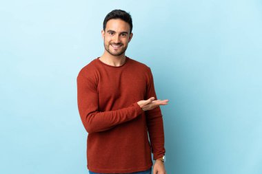 Soyutlanmış arka planda genç yakışıklı bir adam gülümseyerek bir fikir sunuyor.