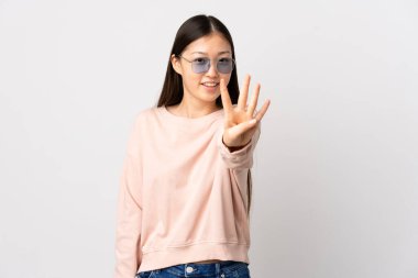 Genç Çinli kız izole edilmiş beyaz arka planda mutlu ve parmakları olan dört kişi sayıyor.