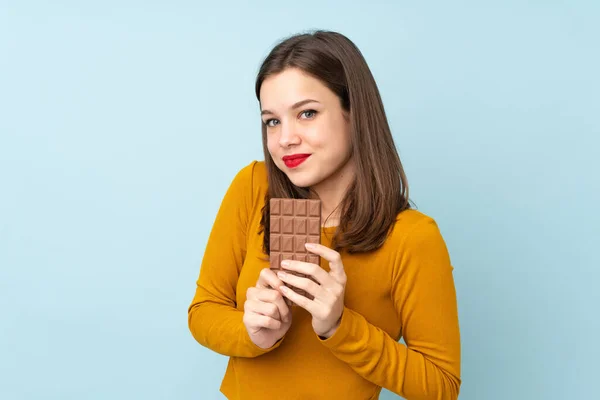 Teenager Dívka Izolované Modrém Pozadí Čokoládovou Tabletu Šťastný — Stock fotografie