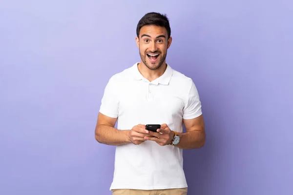 Junger Gutaussehender Mann Auf Violettem Hintergrund Überrascht Und Sendet Eine — Stockfoto