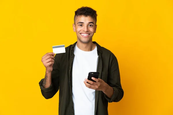 Fiatal Brazil Férfi Elszigetelt Sárga Háttér Vásárlás Mobil Hitelkártyával — Stock Fotó
