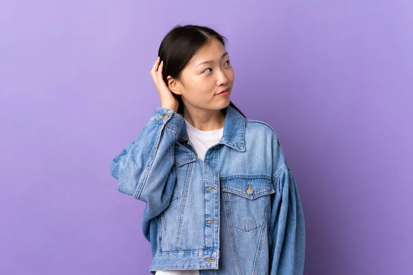 一个年轻的中国女孩在孤立的紫色背景上想出了一个主意 — 图库照片