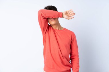 İzole edilmiş mavi arka planda yakışıklı bir adam. Gözlerini elleriyle kapatıyor.