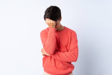 Başı ağrıyan, soyutlanmış mavi arka planı olan yakışıklı bir adam.