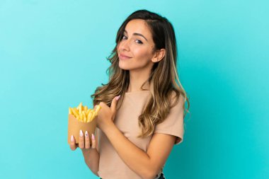 Kızarmış cipsleri soyutlanmış arka planda tutan genç bir kadın gururlu ve kendini beğenmiş.