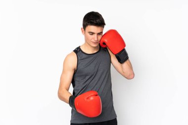 İzole edilmiş beyaz duvarda boks eldivenli genç bir sporcu.